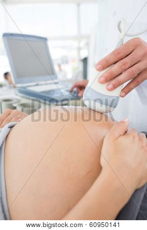 Cropped image of expectant woman receiving ultrasound in hospital