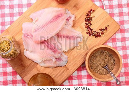 Raw fish tilapia on cutting board and spices