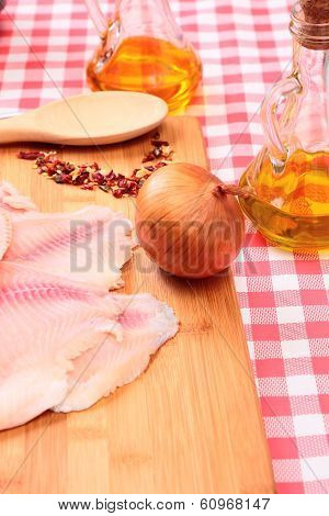 Raw fish tilapia on cutting board and spices