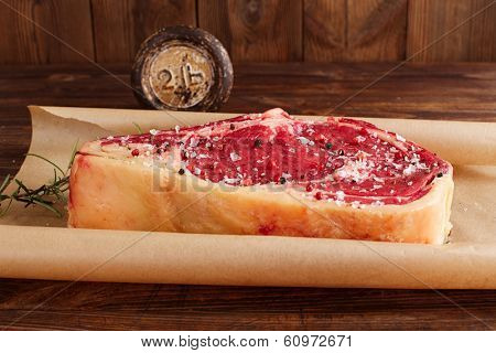 raw beef Rib bone  steak  on paper  and table with 2lb iron weight