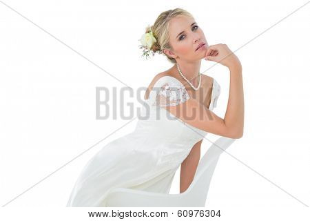 Portrait of confident bride with hand on chin leaning on chair over white background