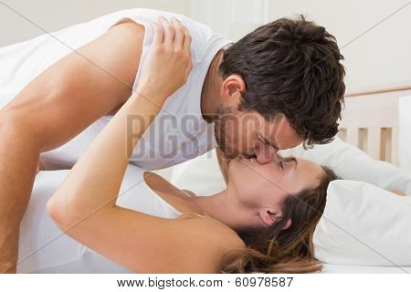 Side view of a relaxed young couple kissing in bed at home