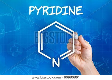 Hand with pen drawing the chemical formula of pyridine