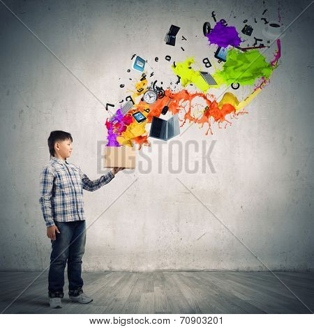 Young boy splashing colorful paint from bucket