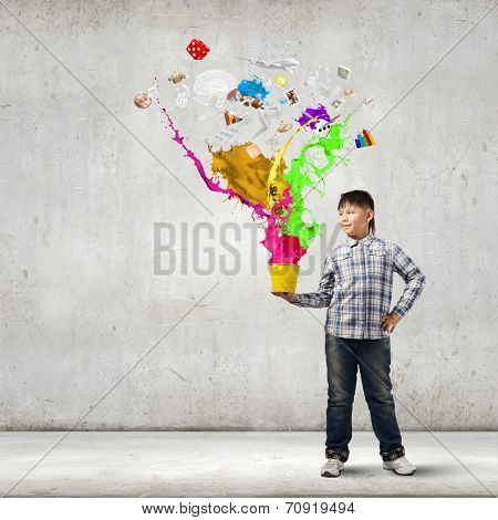 Young boy splashing colorful paint from bucket