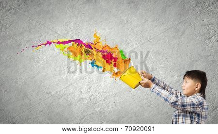Young boy splashing colorful paint from bucket