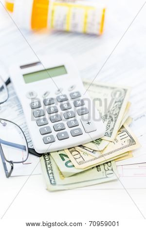 Calculating income tax return with folded cash on a table.
