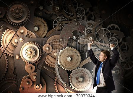 Young businessman fixing gears mechanism with wrench