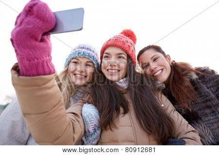 people, friendship, technology, winter and leisure concept - happy teenage girls taking selfie with smartphone outdoors