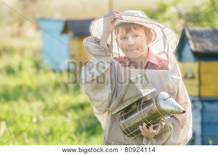 Teenage beekeeper using a smoker on bee yard