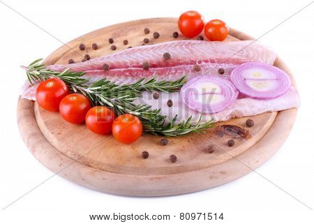 Pangasius fillet on wooden cutting board with cherry tomatoes and spices isolated on white