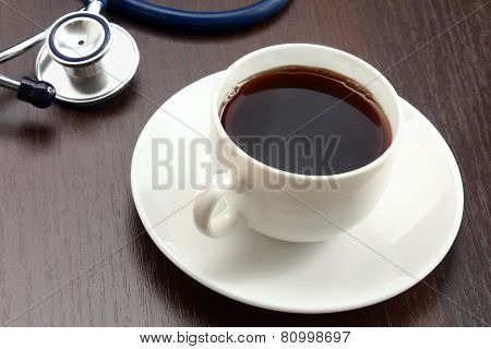 A cup of coffee and a statoscope on a desk