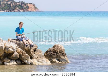 Boy fishing with rod near sea
