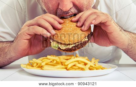 close up photo of man eating burger and french fries