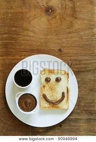 breakfast serving funny face on the plate (toast, chocolate spread and coffee)