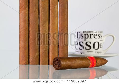Different Cigars And Cup Of Coffee On A  Glass Table