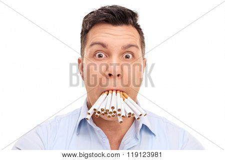Baffled young man with a bunch of cigarettes in his mouth isolated on white background