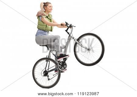 Young woman doing a wheelie on a bicycle isolated on white background