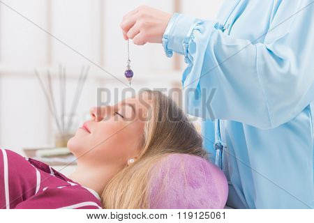 Alternative medicine therapist using pendulum to make a diagnosis