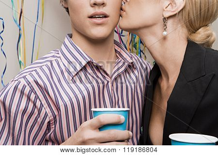 Woman kissing man at office party
