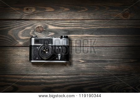 Retro film photo camera on the wooden background.