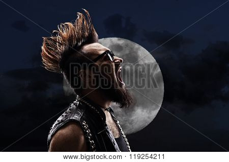 Young man with a Mohawk hairstyle shouting in the night in front of a full moon 