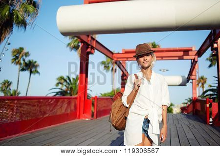 Pretty woman dressed in trendy clothes with backpack on shoulders posing during recreation time
