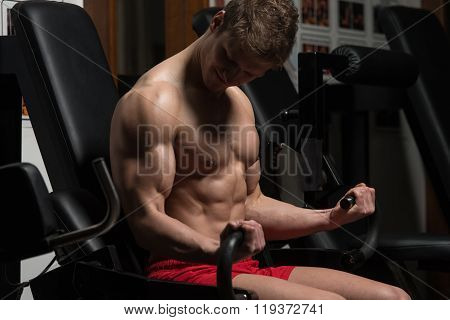 Young Man Doing Exercise For Biceps With Machine