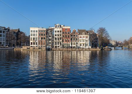 AMSTERDAM NETHERLANDS - 17TH FEBRUARY 2016: Buildings along Staalkade street in Amsterdam. Part of the Amstel canal can be seen.