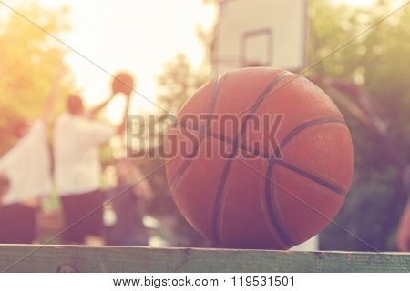 Basketball ball on a bench with defocused players in the background.