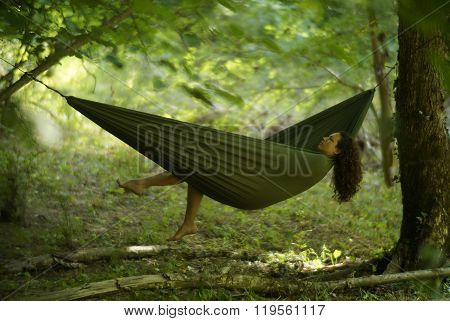 Beautiful young woman relaxing in a hammock deep in the woods.