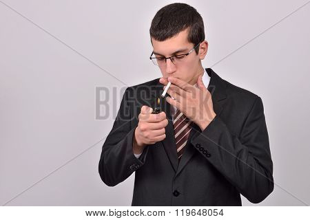 Young Man Dressed In Tuxedo Lighting Cigarette In Studio