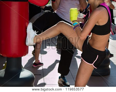 Young Girl Doing Kickboxing With Gloves In Fitness Class With Red Punching Bag