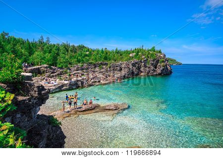 amazing natural rocky beach view and tranquil azure clear water with people in background