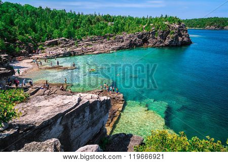 amazing natural rocky beach view and tranquil azure clear water with people in background on sunny b