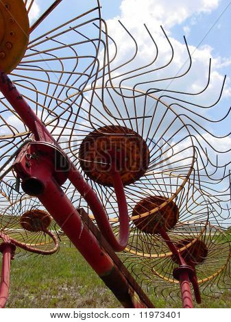 An abstract view of the underside of a hayrake with the blades turned toward the sun.