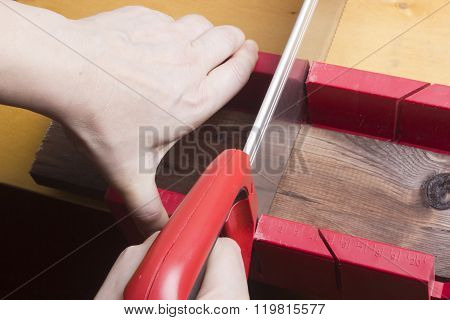 Close Up Of Builders With Arm Saw Sawing Board