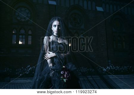 Mysterious woman in black dress near chirch