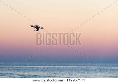 Flying drone with camera on the sky at sunset