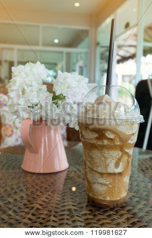 Iced Frappe Coffee In Plastic Mug Put On The Rattan Weave Table In Coffee Shop Cafe