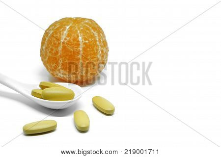 Fresh orange fruit and pills of vitamin C in spoon on white background, medical and healthcare concept