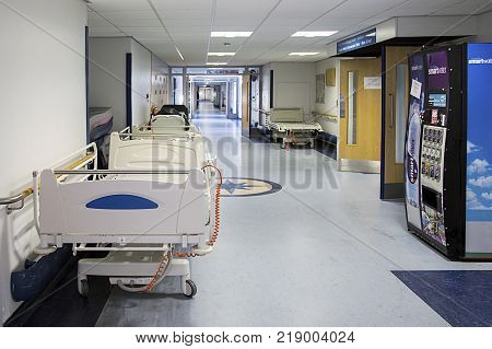 Swansea, UK: November 25, 2017: An empty corridor in a hospital. The corridor is clean with spare hospital gurneys and a vending machine selling fresh drinking water.