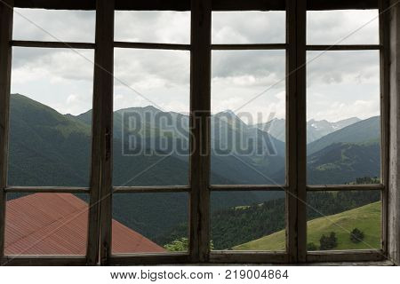 view of the mountains through a paneless window in the remote mountain village of Bochorna in the Tusheti region of Georgia
