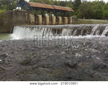 old dam with clear flowing water with the background forest