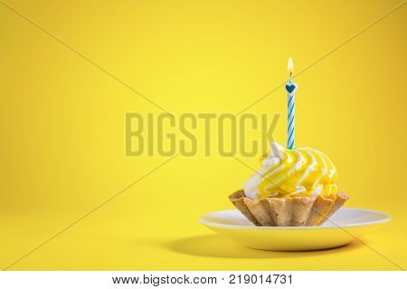 Tasty Birthday cupcake with candle on yellow background with copy space. Delicious muffin on color background. Happy birthday concept.