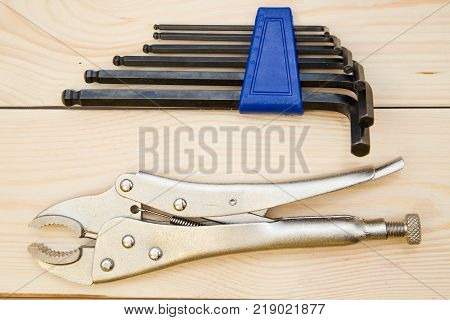 A set of new repair tools-pilers and hex keys on a light uncolored wooden background. Close up. Top view. Space for your text or pruduct display.