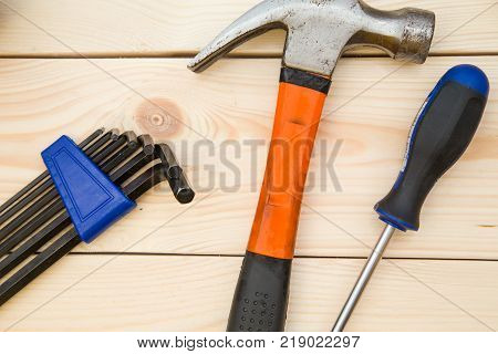 Renovating a house. A set of repair tools- hex keys, a hammer and a screwdriver on a light uncolored wooden background. Close up. Top view. Space for your text or pruduct display.