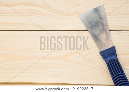Repairing and construction concept. A close up of a plastering trowel on a light uncolored wooden background. Top view. Space for your text or pruduct display.