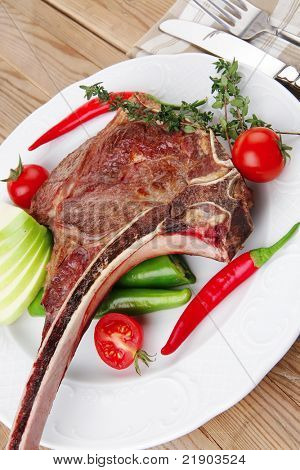 santoreggia: alla griglia ricambio rib su piatto bianco con pepe timo e pomodoro sul tavolo di legno