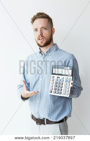 Portrait of irritated young manager holding calculator with presenting gesture. Cheated investor showing loss. Finance or disadvantage concept.